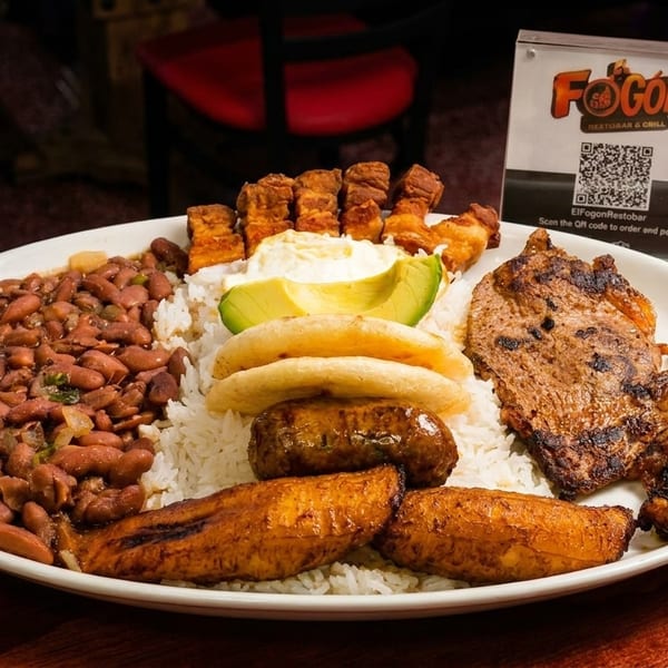 A large platter of Colombian bandeja paisa with grilled steak, beans, rice, plantains, avocado, and chicharron.